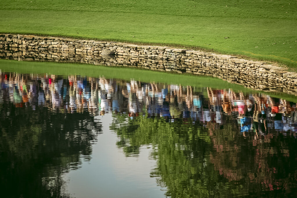 fans reflect in the pond at Quail Hollow